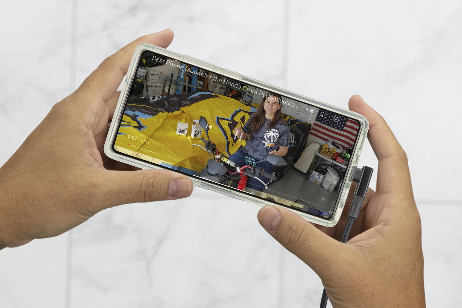 hands holding Note20 phone with video playing and right angle cable connected