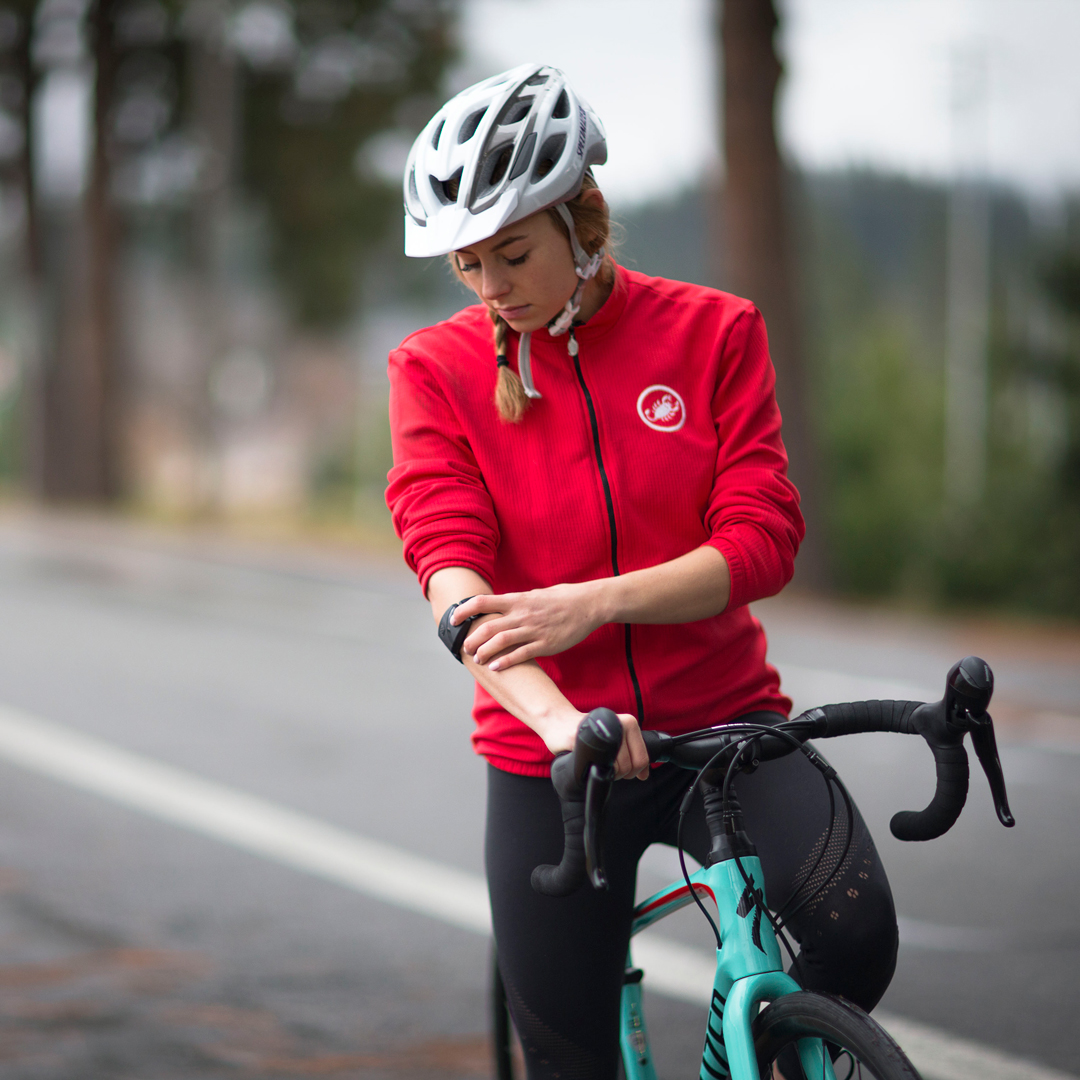 woman riding bike while checking armband heart rate monitor