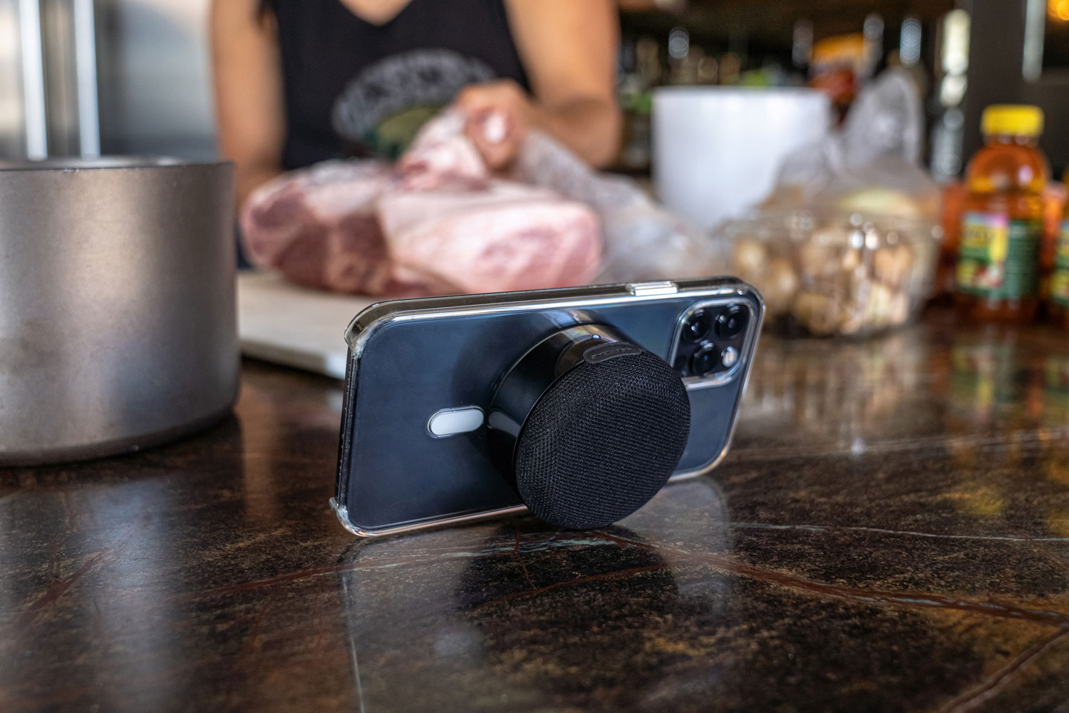 iphone on kitchen counter using compact bluetooth portable speaker as kickstand