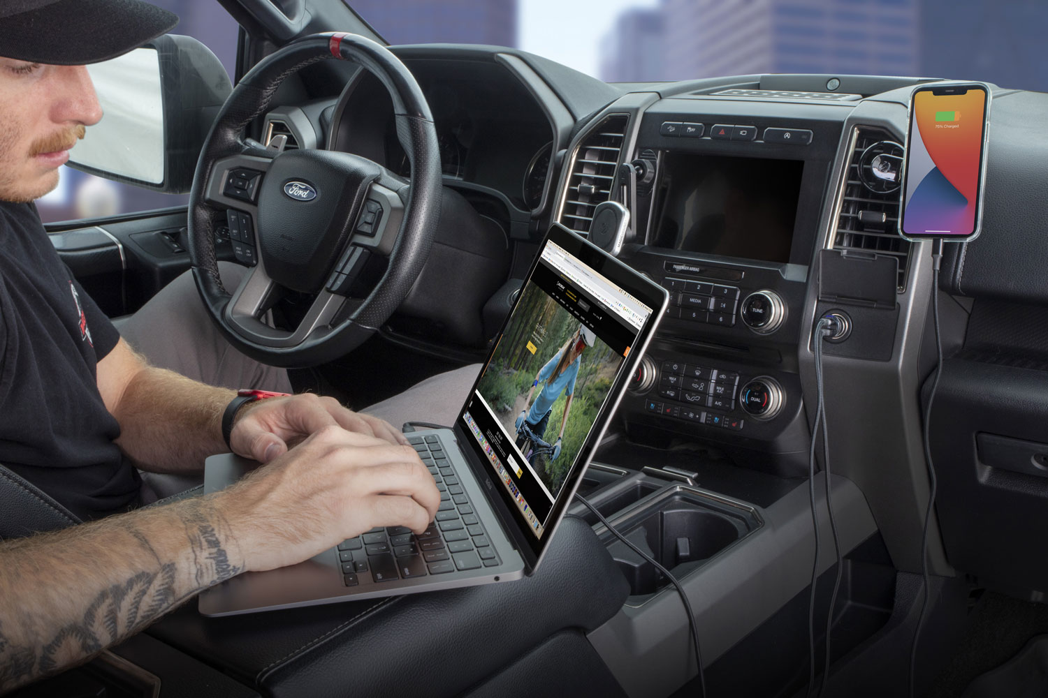 man using laptop while charging via Scosche dual port car charger and iphone charging while mounted to car vent