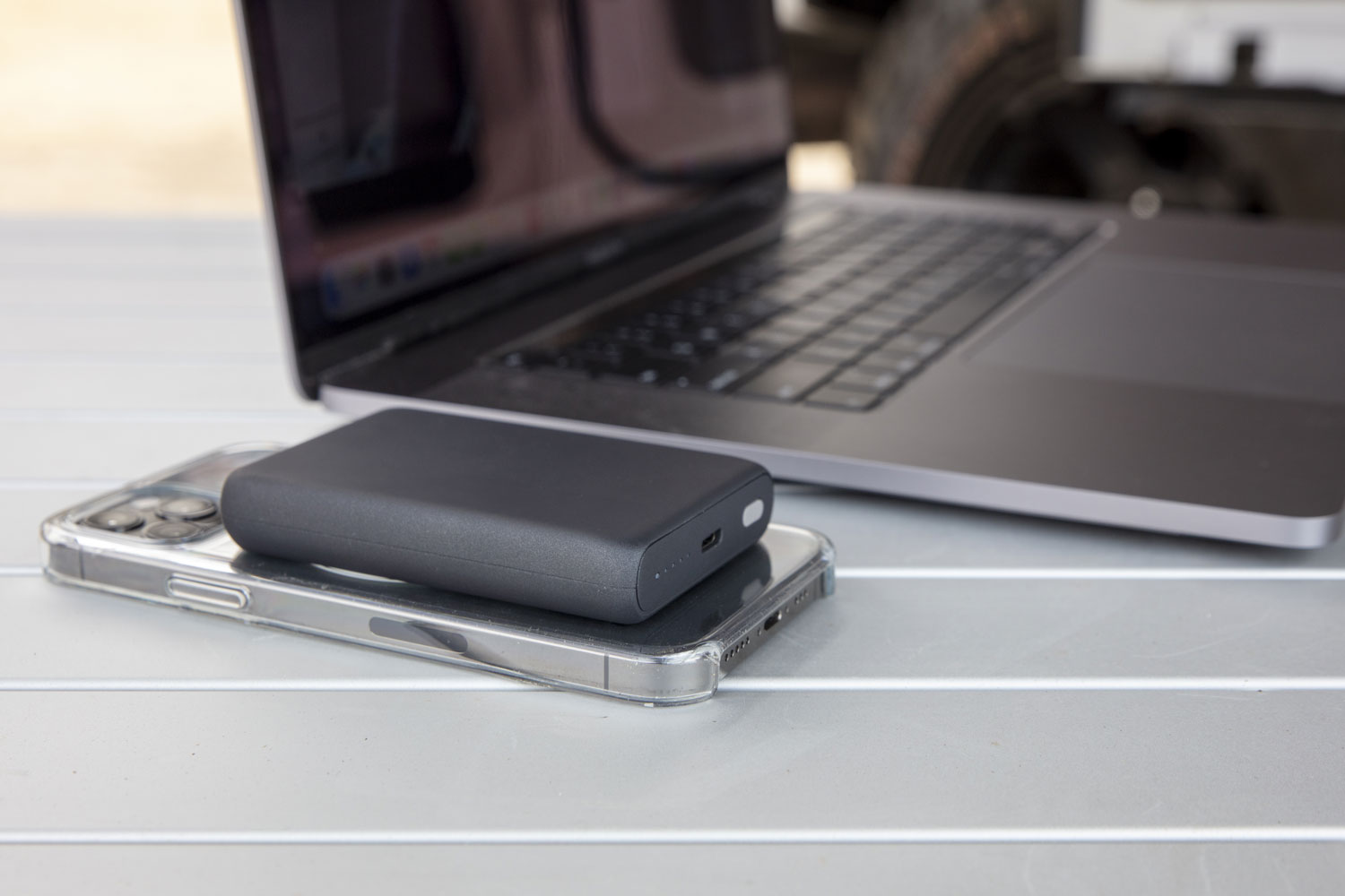 iphone with MagSafe wireless power bank on table next to laptop